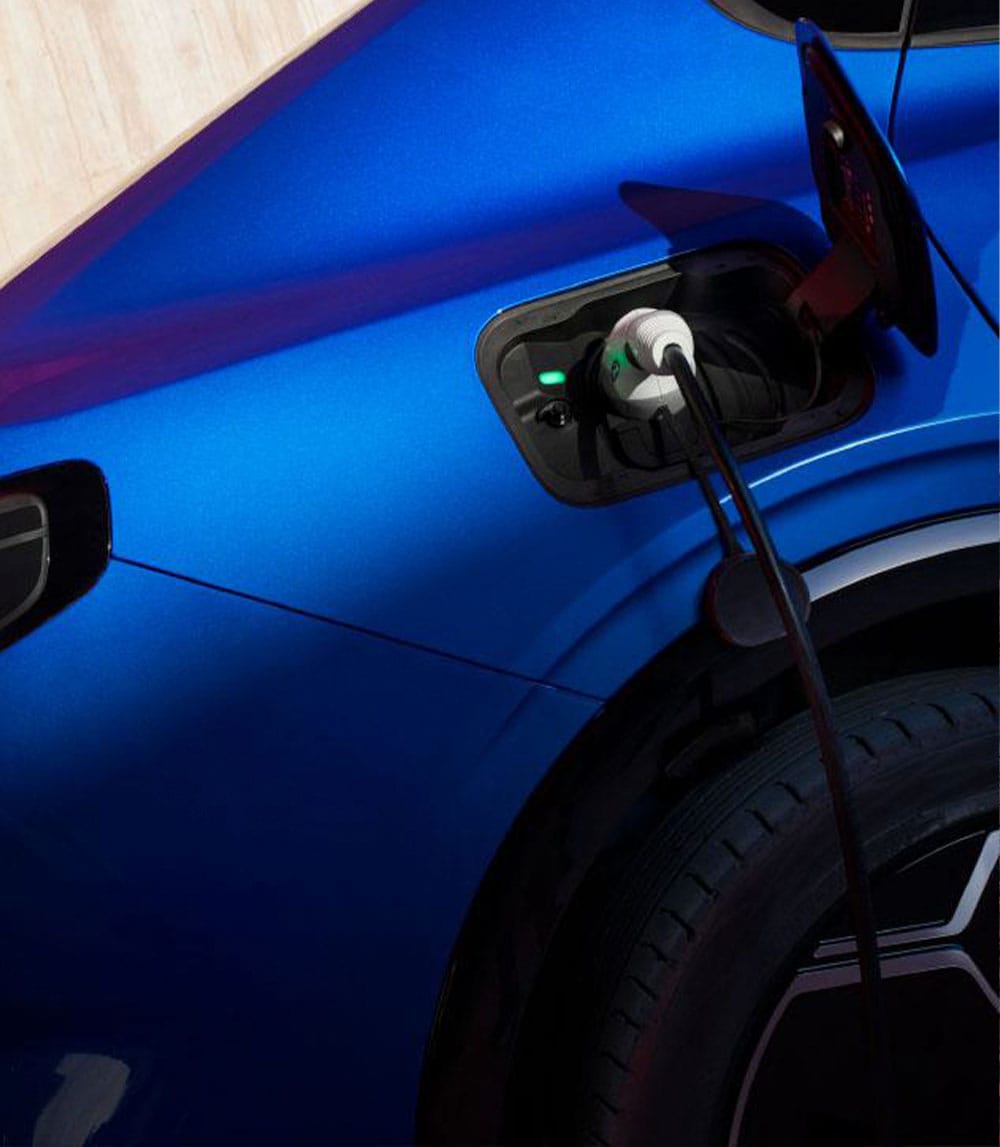 Une voiture Ford bleue est en charge, avec un câble de recharge branché dans le port ouvert.