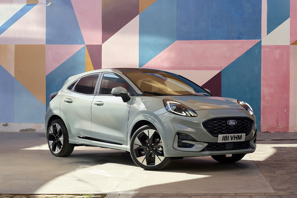 SUV Ford Puma couleur argent garé devant une fresque géométrique colorée.