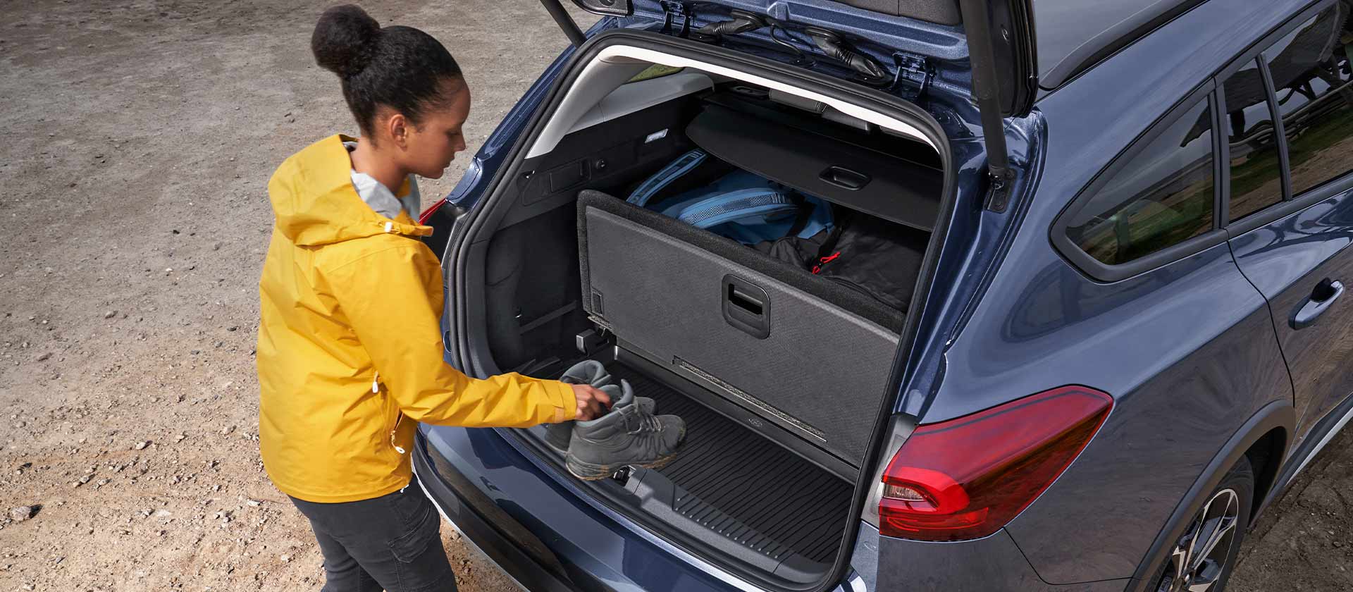 Une femme charge des chaussures dans le coffre d’une Ford Focus.