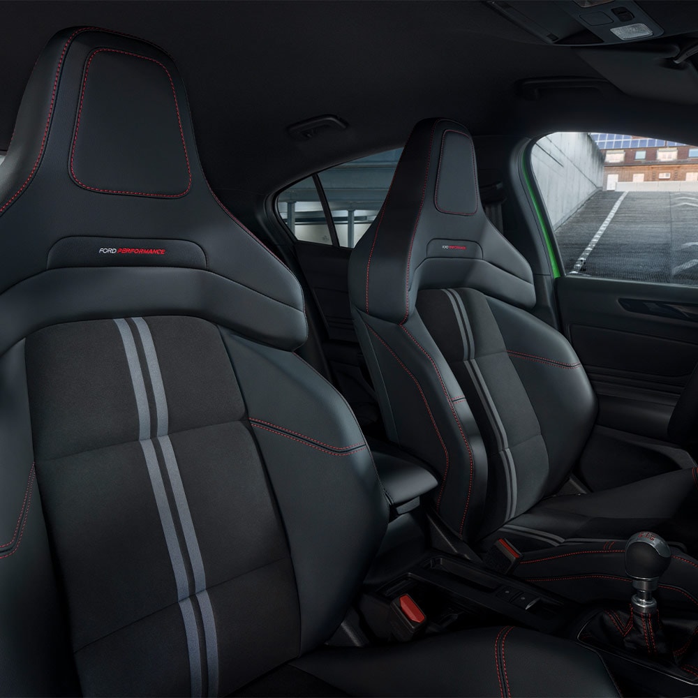 Gros plan sur les sièges Sport de la Ford Focus ST avec un rembourrage foncé et des surpiqûres contrastées rouges.