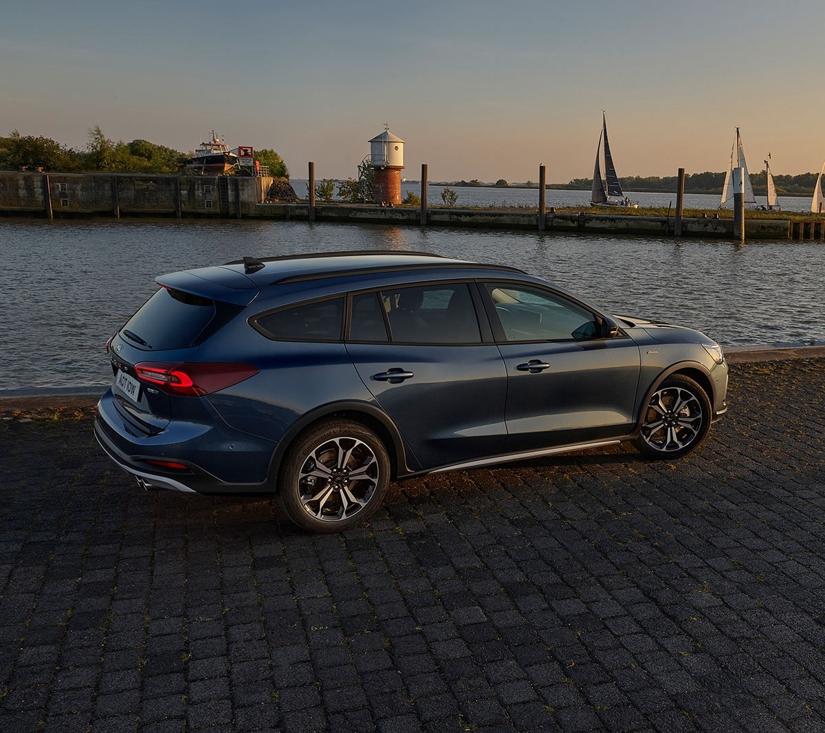 Ford Focus Active couleur bleue. Vue arrière aux trois quarts, garée devant un lac.