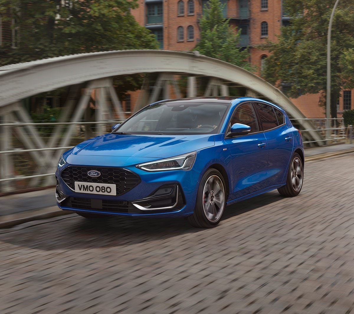 Ford Focus couleur bleue. Vue de face aux trois quarts, roulant sur un pont.