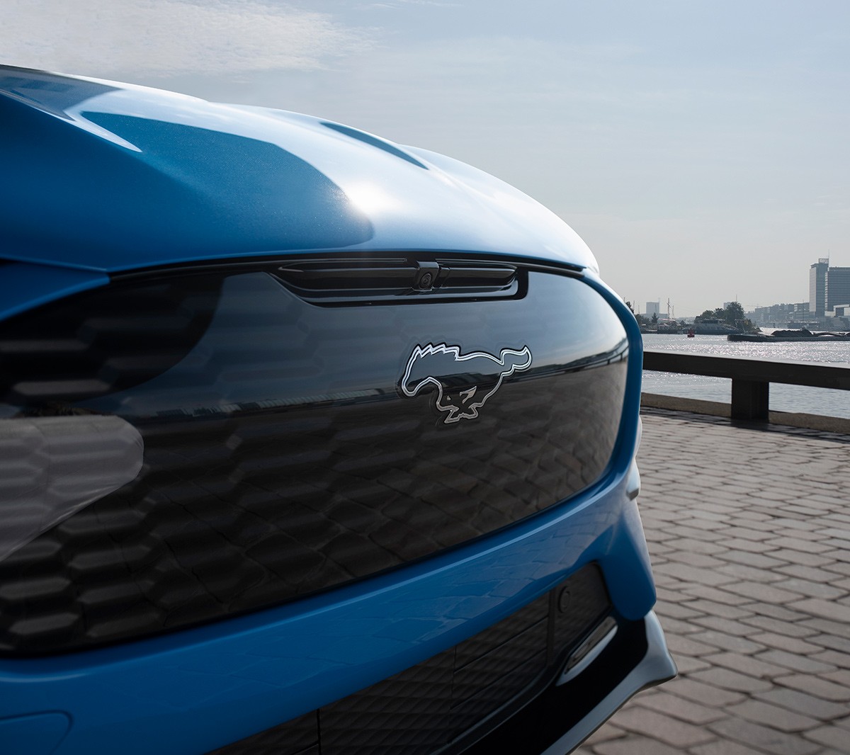 Ford Mustang Mach-E GT couleur bleue. Vue de face aux trois quarts sur le cheval  Mustang.