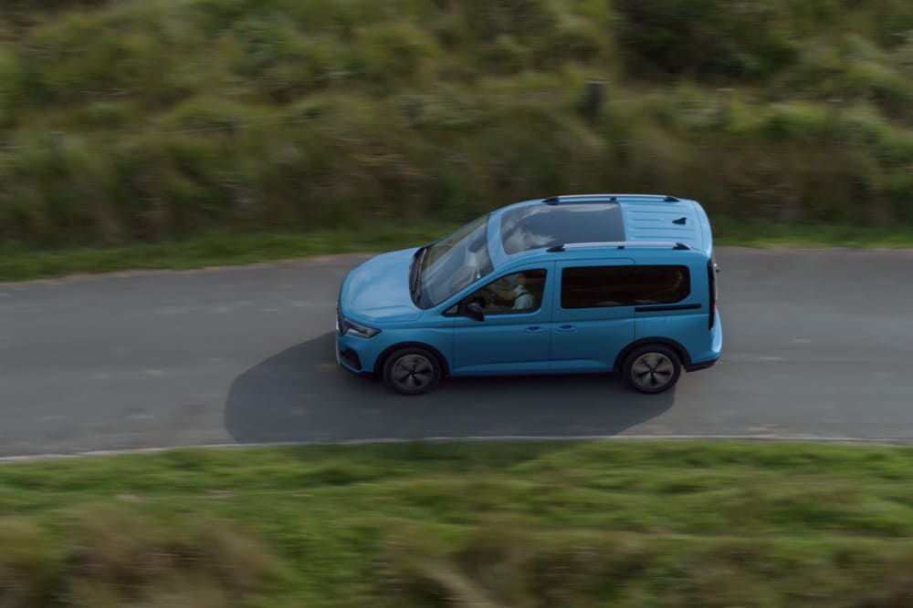 Ford Tourneo Connect couleur bleu clair, vue latérale aérienne, roulant sur une route de campagne