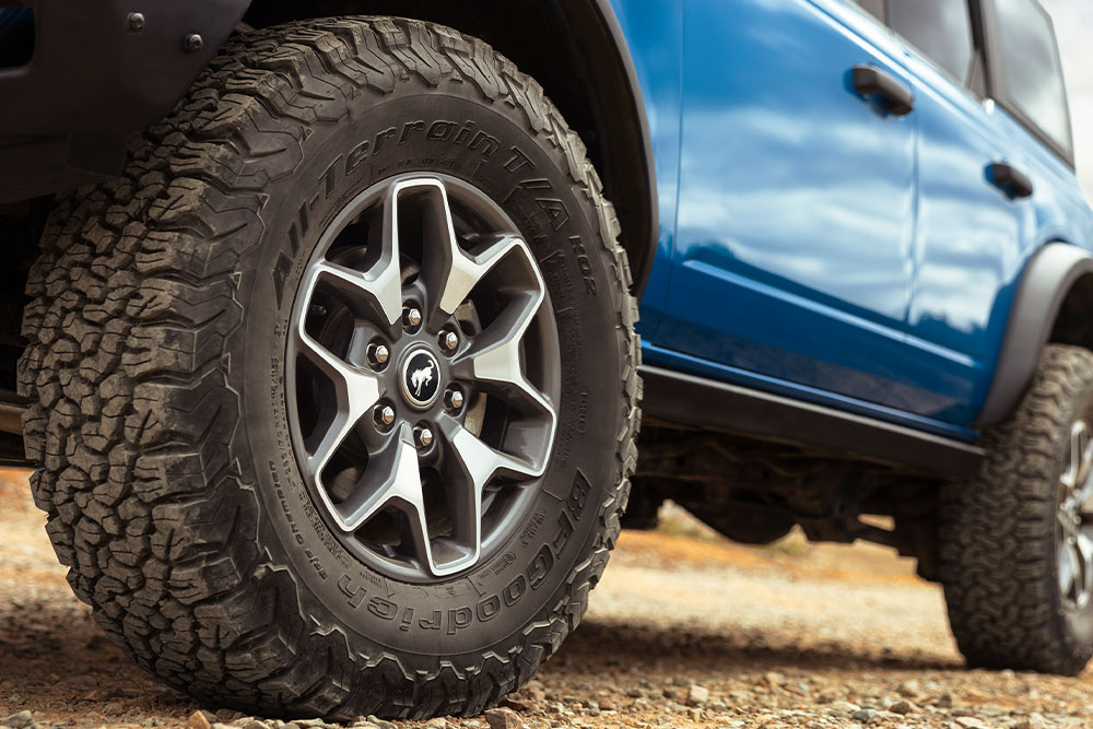 Gros plan des pneus tout-terrain d'un Ford Bronco bleu.