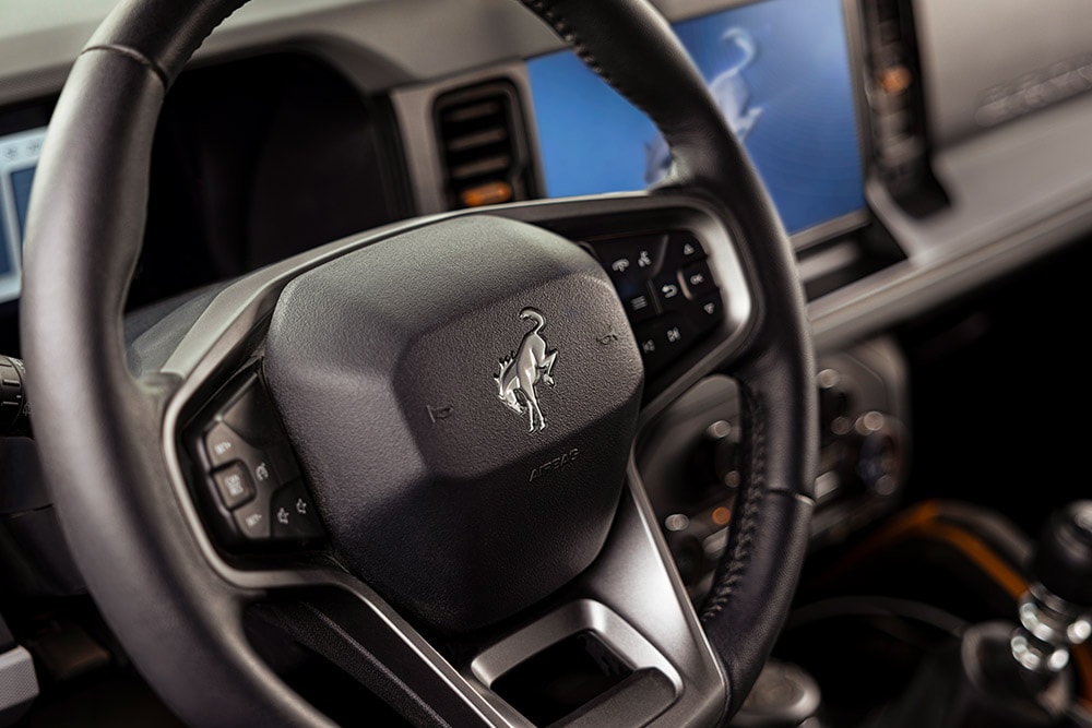 Gros plan du volant en cuir avec le logo du Ford Bronco.