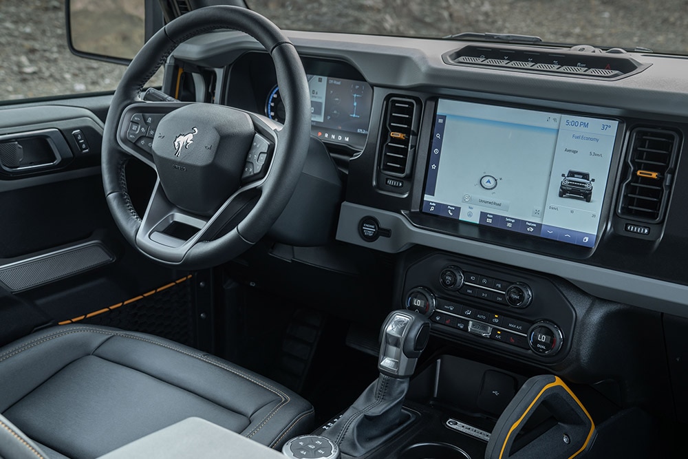 Vue de l'intérieur d'un Ford Bronco, incluant le volant en cuir et le pavé tactile intégré.