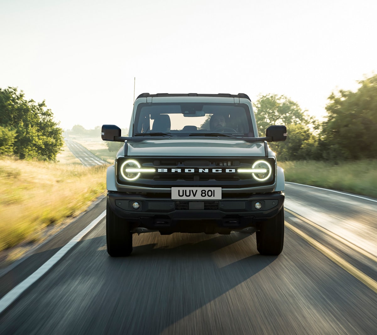 Ford Bronco couleur grise. Vue de face, roulant sur une route de campagne.