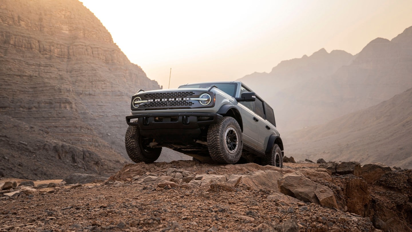 Ford Bronco en gris. Vue de face traversant un paysage de montagne