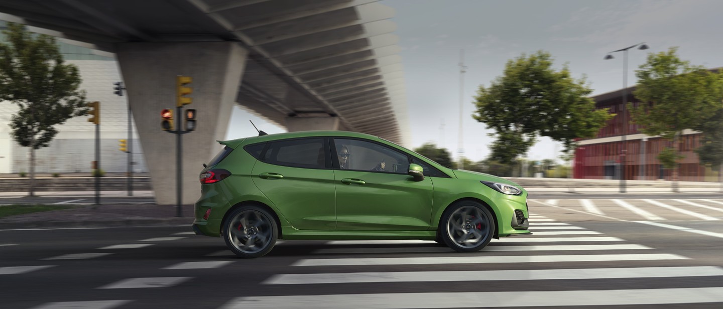 Ford Fiesta ST couleur verte. Vue latérale, roulant sous un pont.