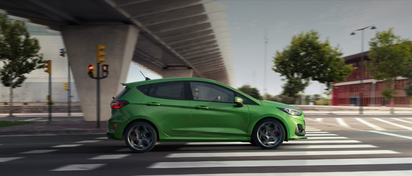 Ford Fiesta ST couleur verte. Vue latérale, roulant sous un pont.