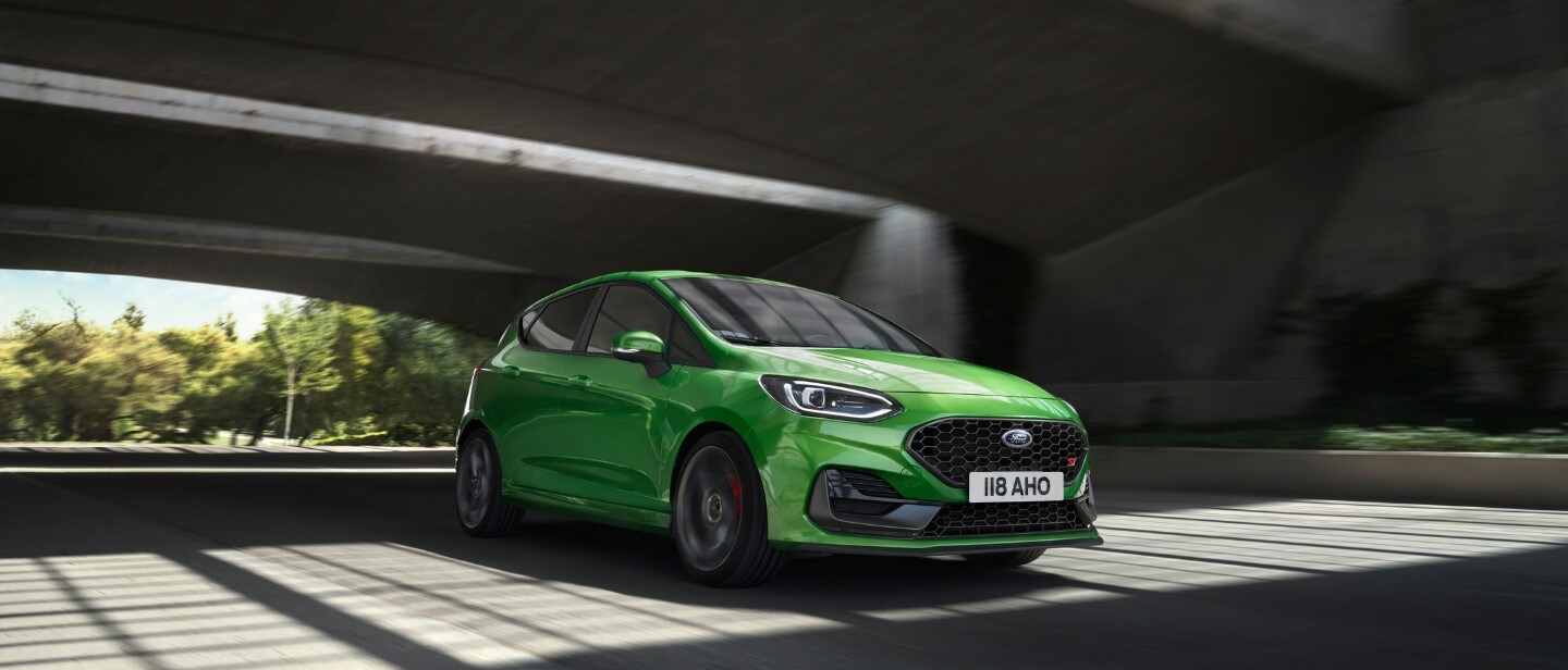 Ford Fiesta ST couleur verte. Vue avant aux trois quarts, roulant sous des ponts.