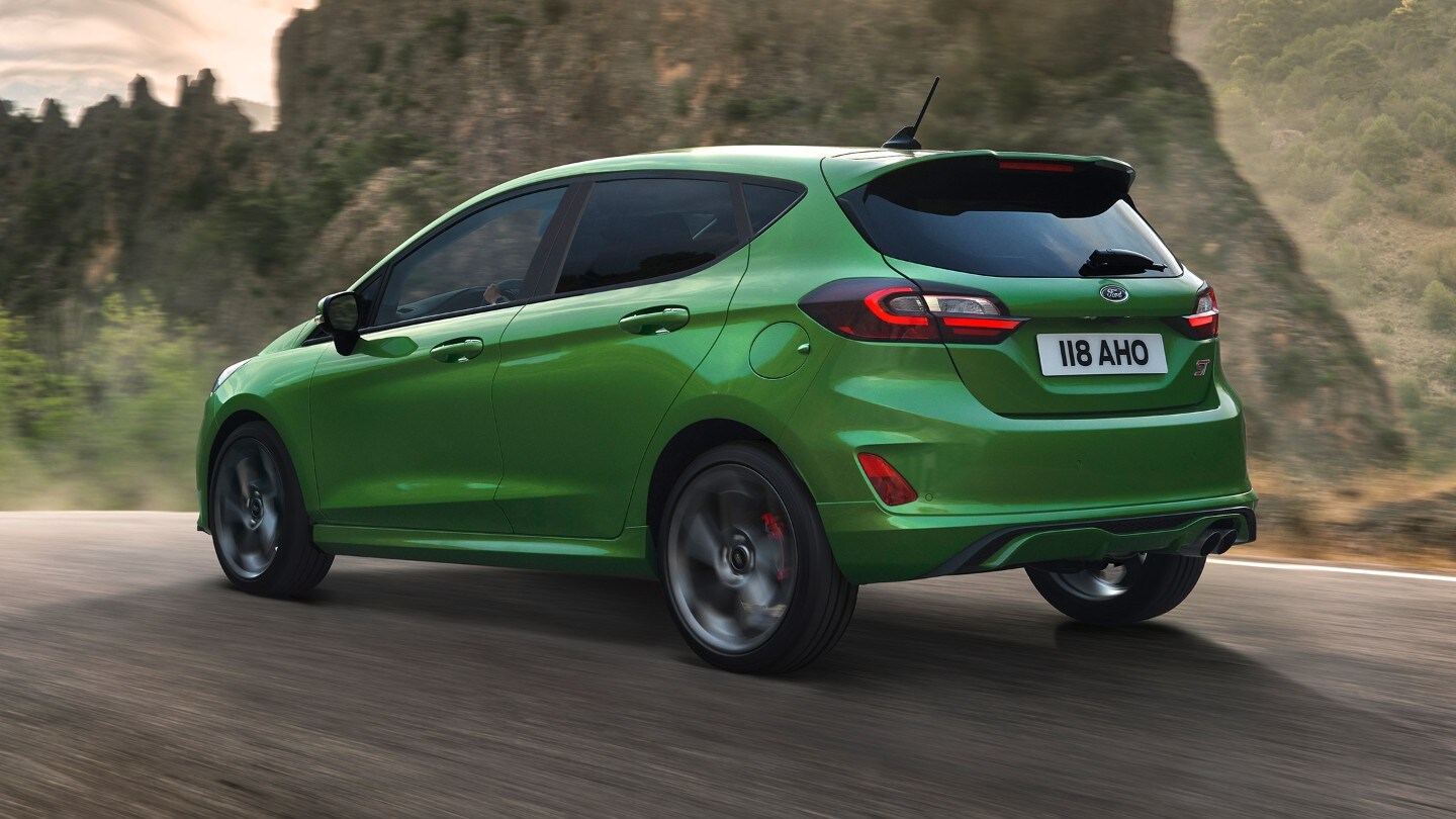 Ford Fiesta ST couleur verte. Vue arrière aux trois quarts, roulant sur une route de montagne.