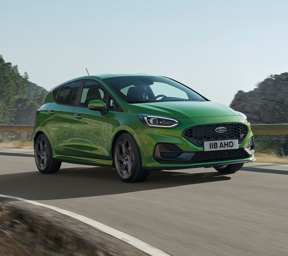 Ford Fiesta ST couleur verte. Vue de face aux trois quarts, roulant sur une route de montagne.