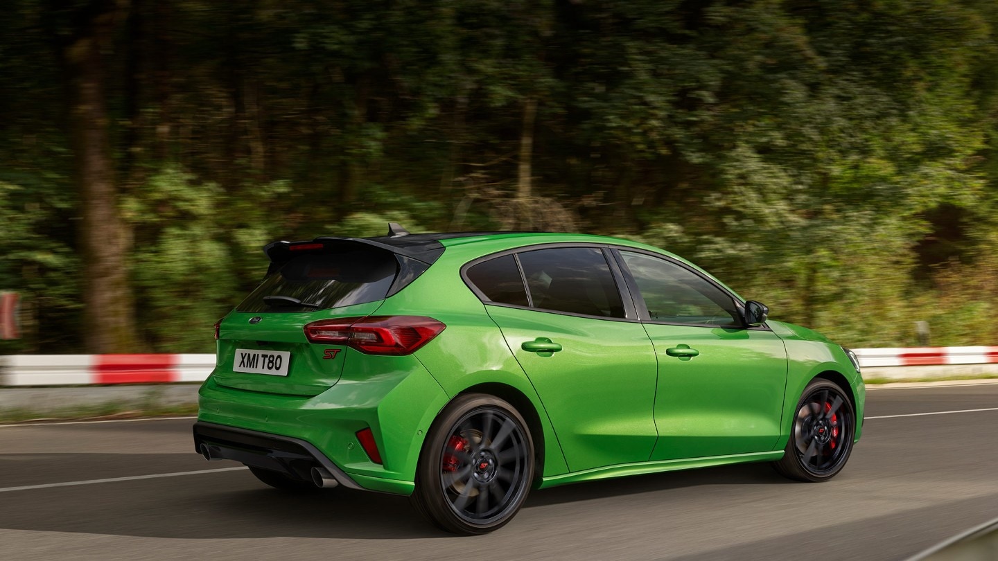 Ford Focus ST couleur verte. Vue arrière aux trois quarts, roulant sur une route.