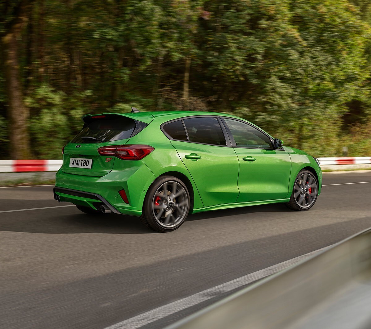 Ford Focus ST couleur verte. Vue arrière aux trois quarts, roulant sur une route.