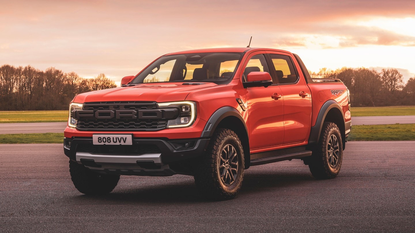 Ford Ranger Raptor couleur rouge, vue de face aux trois quarts, roulant au crépuscule