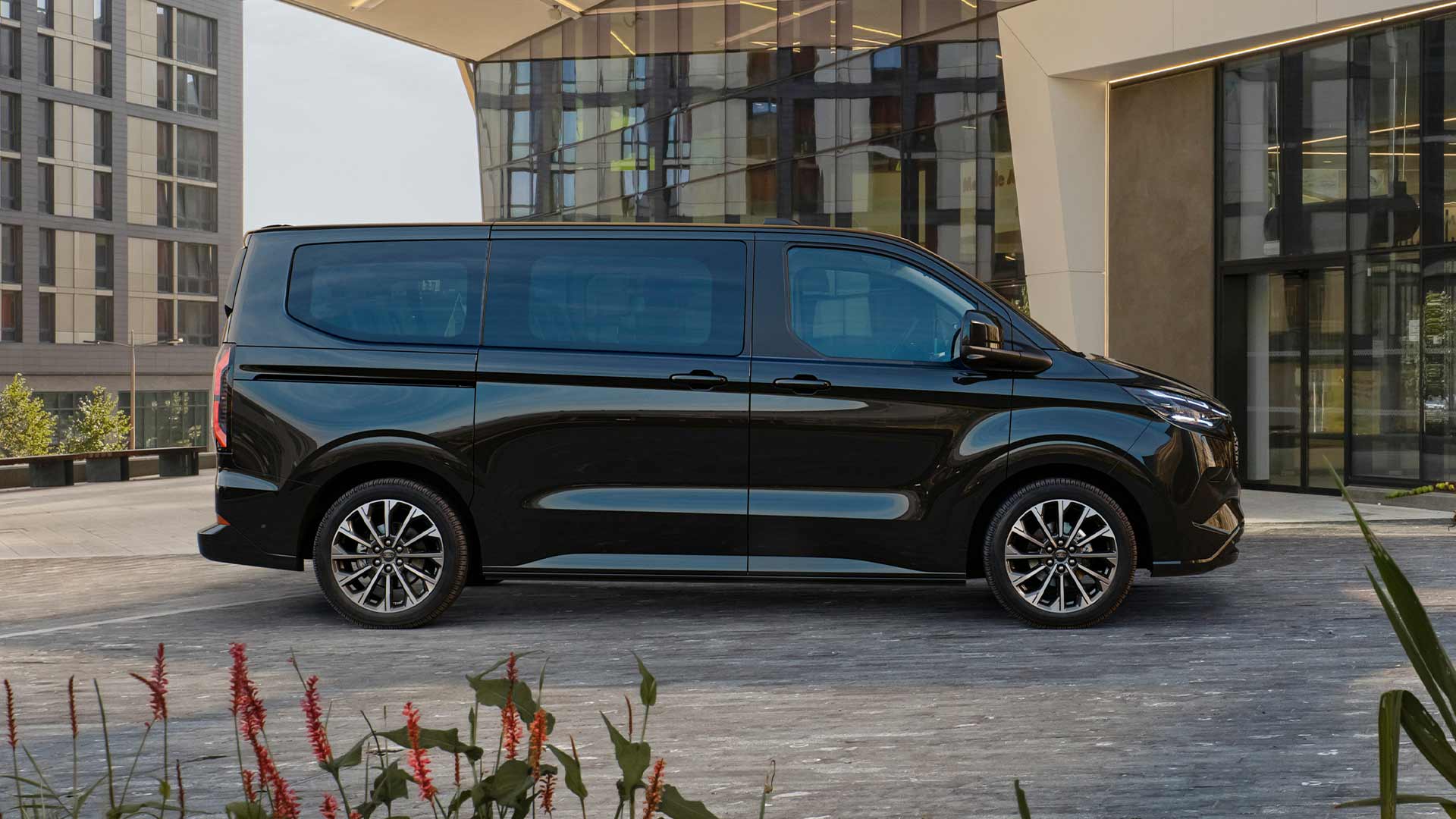 Ford E-Tourneo Custom noir garé devant un bâtiment moderne