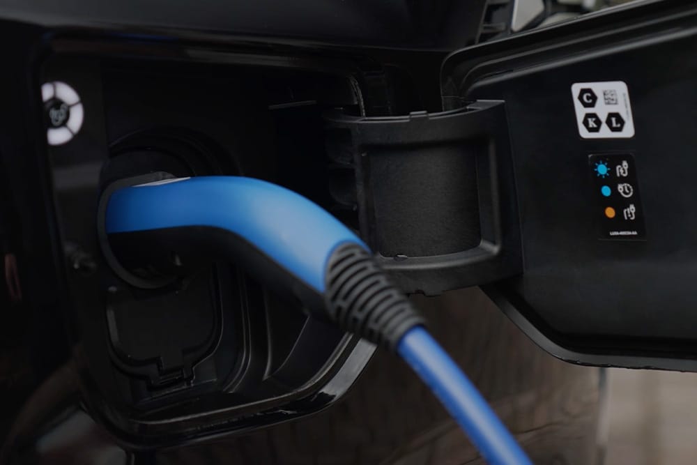 Gros plan d'un câble de recharge bleu dans la prise de recharge d'un véhicule électrique