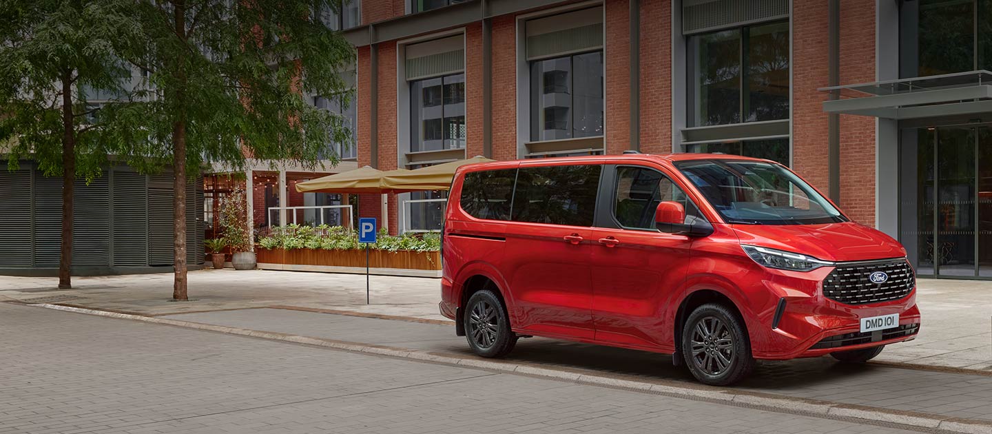 Ford Tourneo Custom rouge garée dans une rue en ville