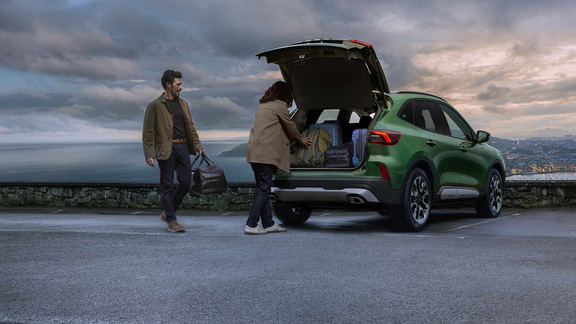 Deux personnes chargent plusieurs valises dans le coffre spacieux du Ford Kuga.