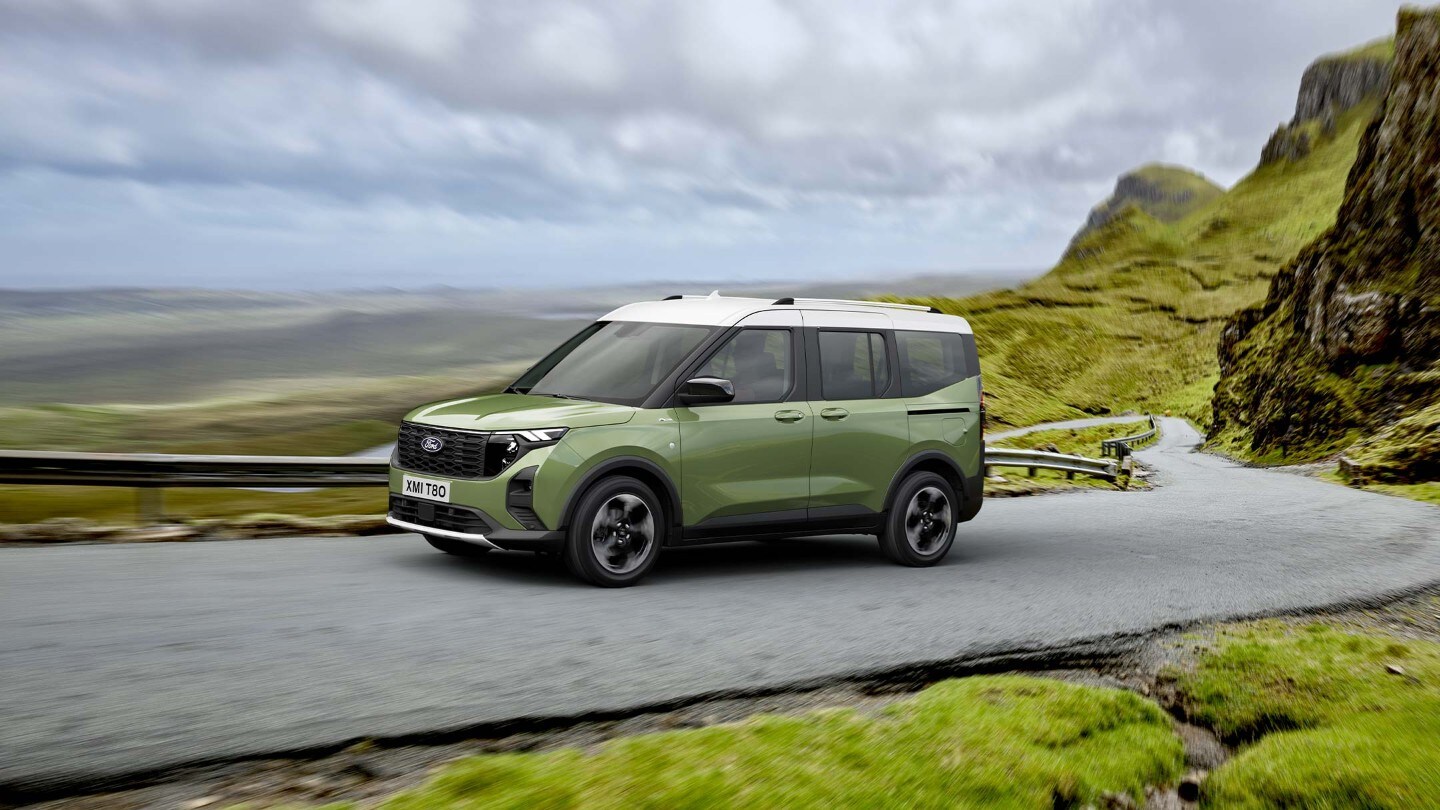 Ford Tourneo Courier couleur verte, vue latérale, roulant sur une route de montagne