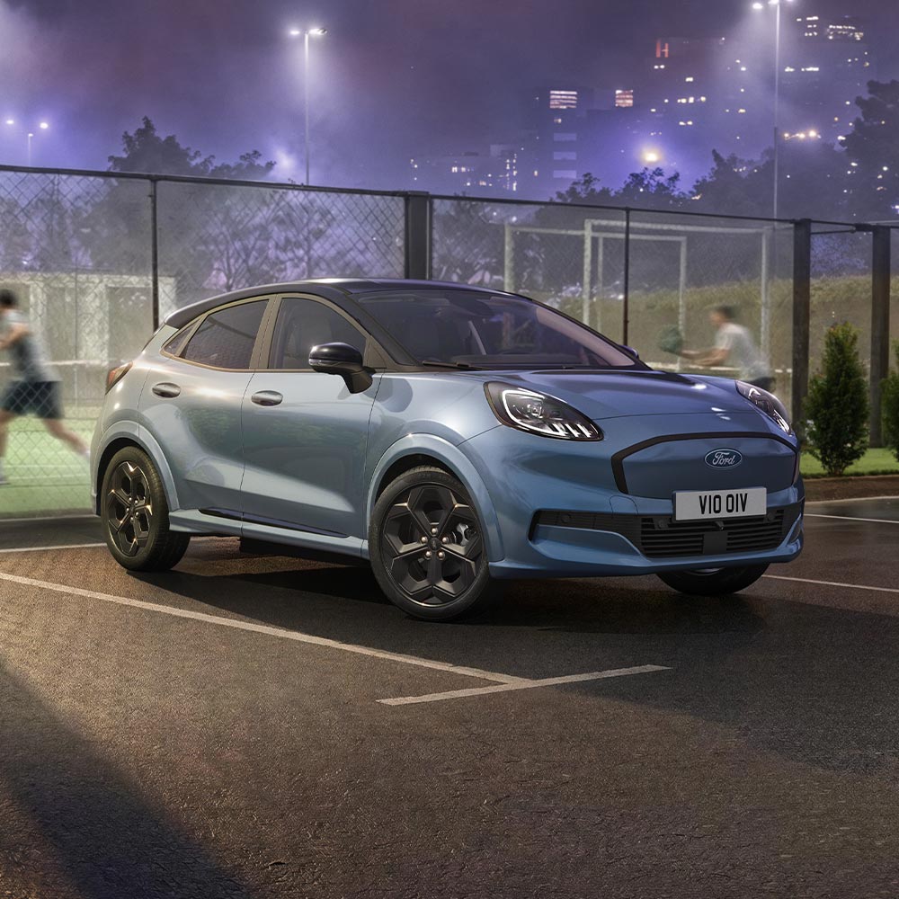 Un Ford Puma Gen-E en édition limitée, de couleur Vapor Blue et équipé de la technologie BlueCruise, est garé à côté d’un terrain de padel en plein air.