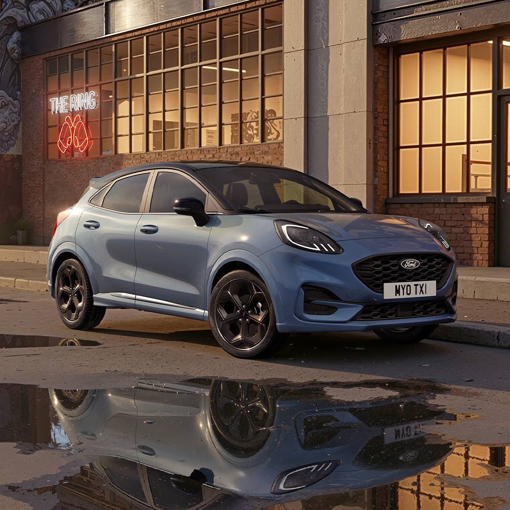 Un Ford Puma dans la teinte spéciale Vapour Blue stationné dans une rue urbaine faiblement éclairée.