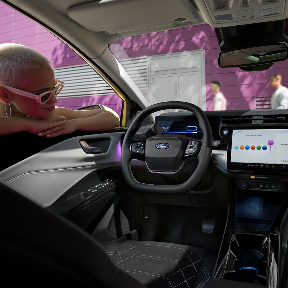 L’intérieur de la Ford Puma Gen-E® électrique avec une personne qui regarde le grand écran d’infodivertissement par la vitre.