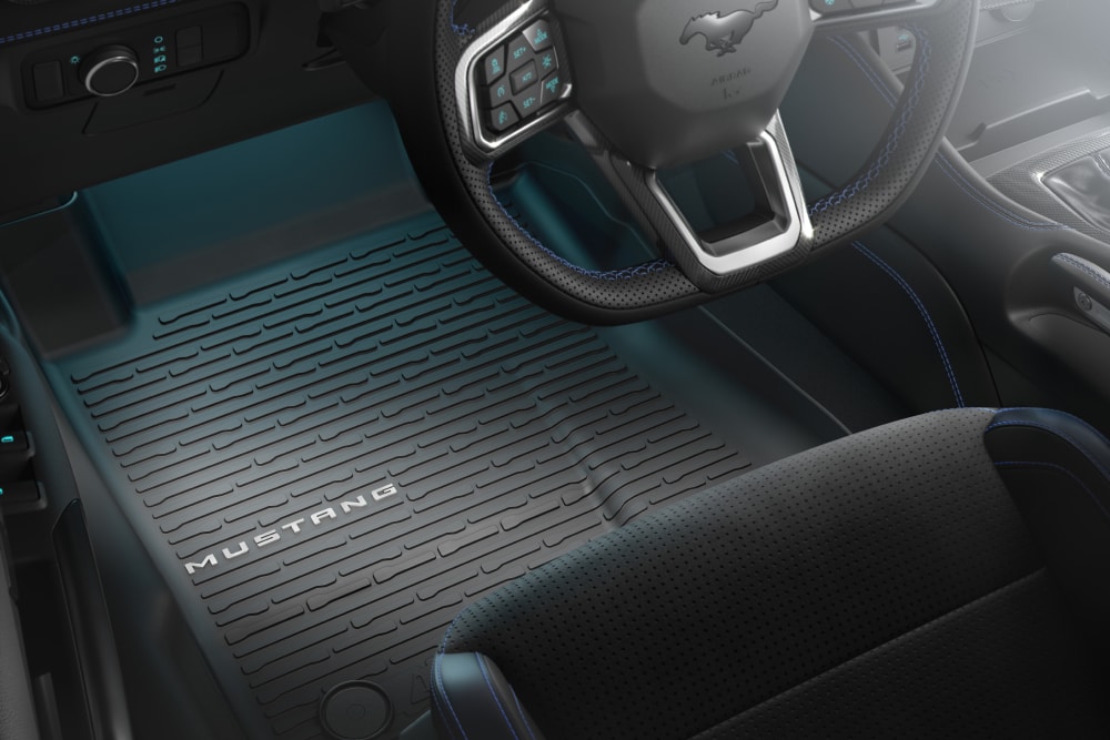 Vue intérieure d'une Ford Mustang montrant le volant et un tapis de sol toutes saisons avec le logo « MUSTANG ».