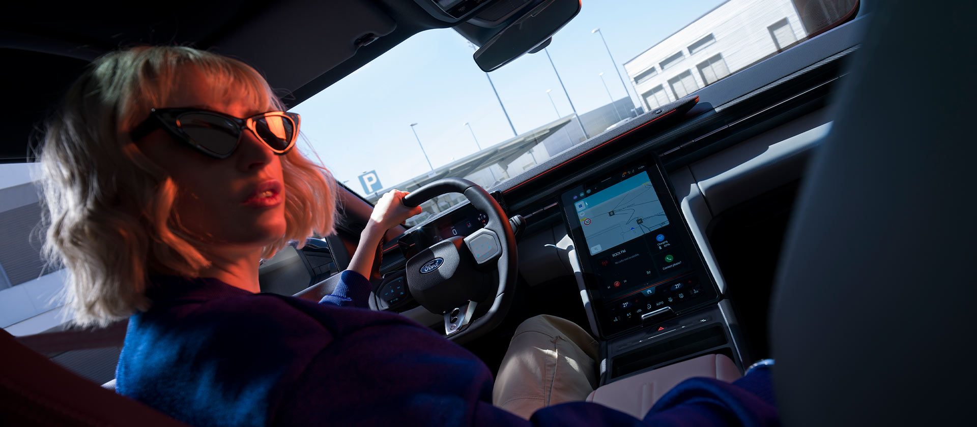 Une femme est assise sur le siège du conducteur d’une Ford Capri® stationnée, volant et grand écran tactile SYNC® Move visibles.