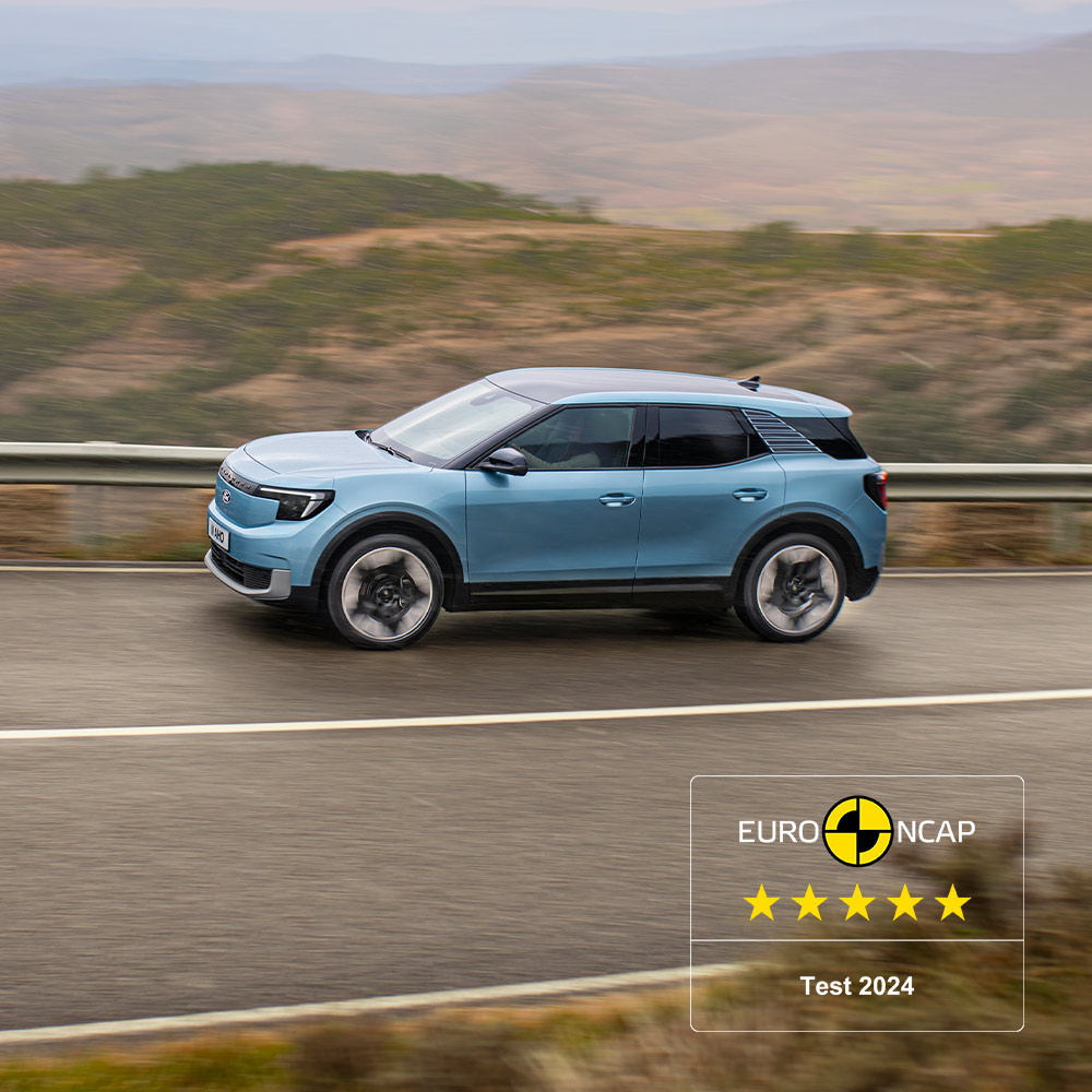 Un Ford Explorer bleu sillonnant une route de montagne, avec le logo Euro NCAP 2024 à cinq étoiles dans le coin supérieur gauche. 