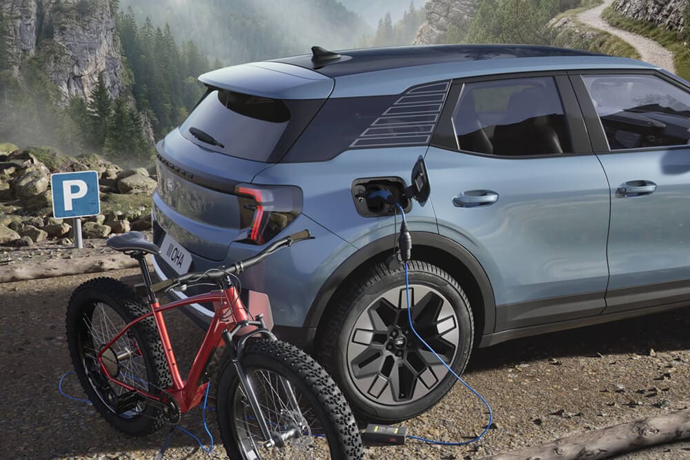 Un vélo électrique en charge depuis un Ford Explorer®, un paysage montagneux en arrière-plan.
