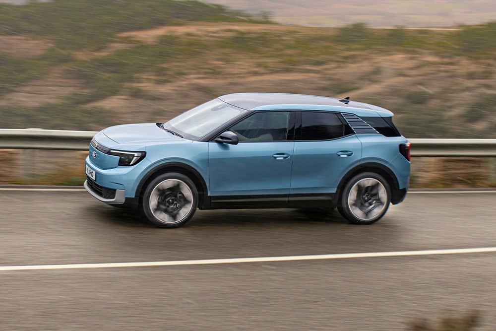Un Ford Explorer bleu sillonnant une route de montagne, avec le logo Euro NCAP 2024 à cinq étoiles dans le coin supérieur gauche. 