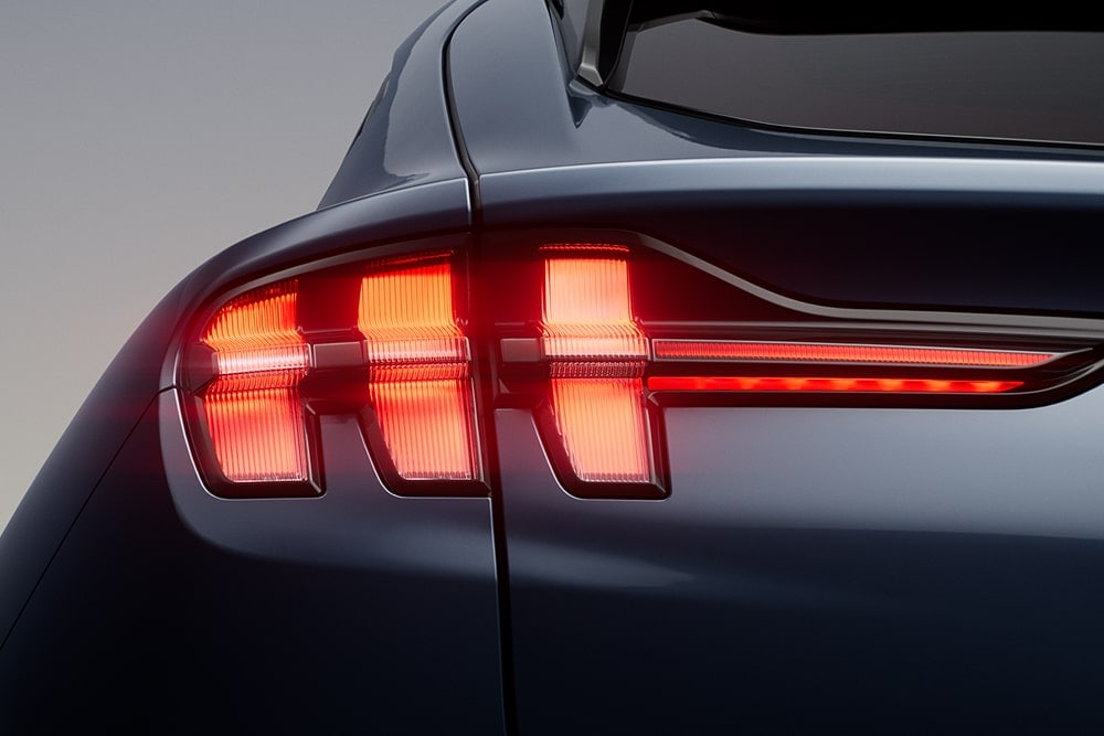 Gros plan sur les trois feux arrière allumés d’une voiture de sport Ford Mustang Mach-E.