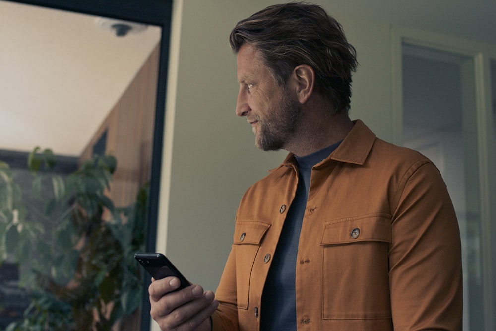 Homme vêtu d’une veste jaune et tenant un téléphone portable