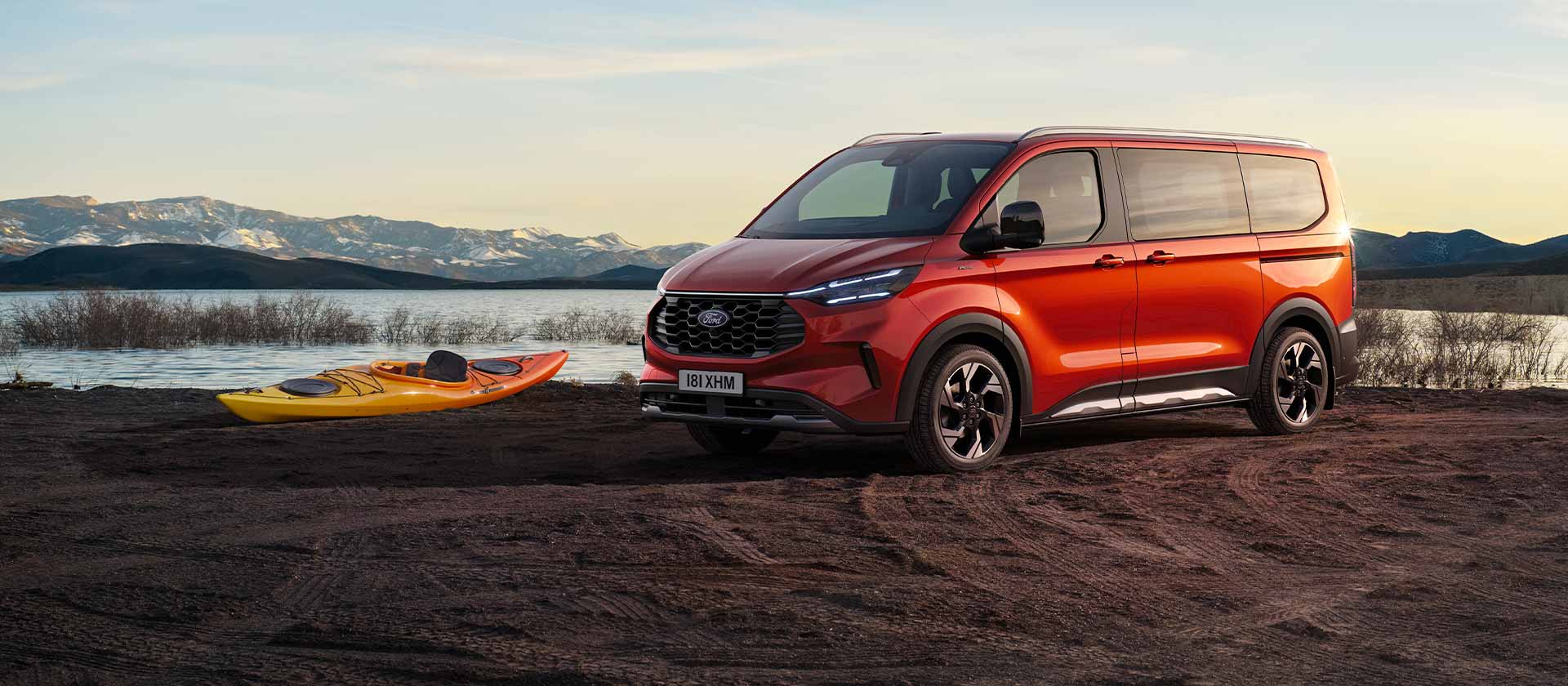 Ford Tourneo Custom rouge garé près d'un lac avec un kayak.  