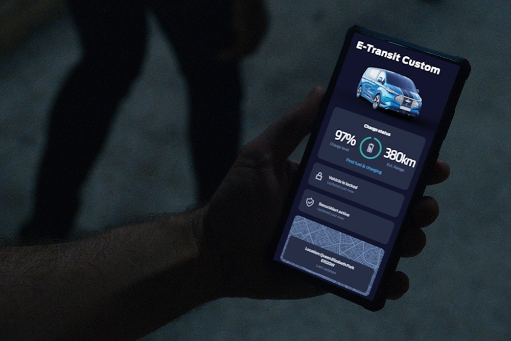 Smartphone affichant l'E-Transit Custom dans l'application FordPass avec l'état de charge et la localisation