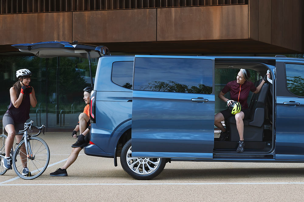 Vue latérale du tout nouveau Tourneo Custom avec des personnes autour 