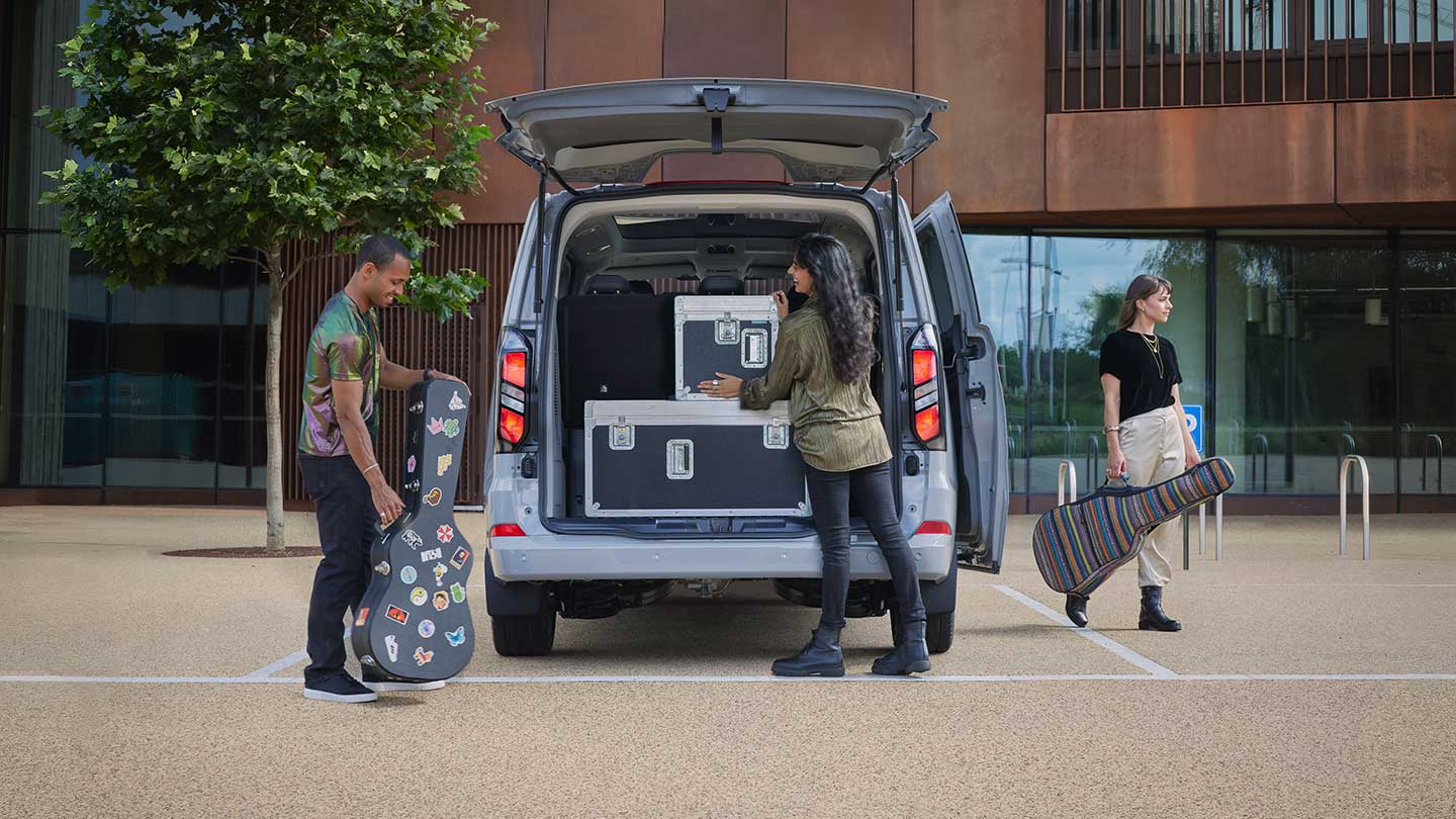 Des personnes qui placent des bagages à l’arrière du tout nouveau Tourneo Custom