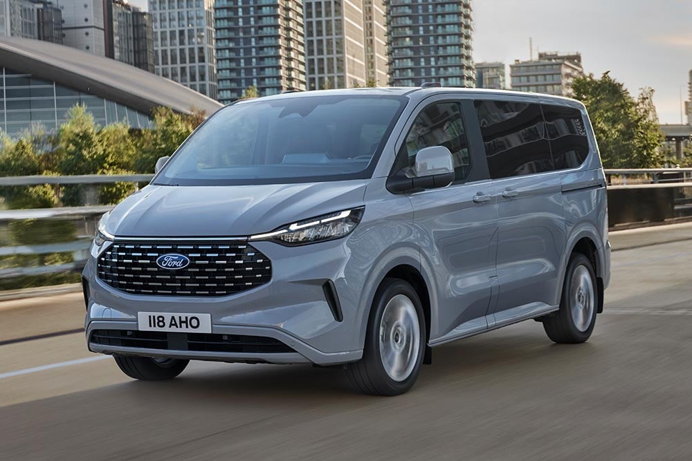 Silberner Ford Tourneo Custom fährt auf einer Stadtstrasse