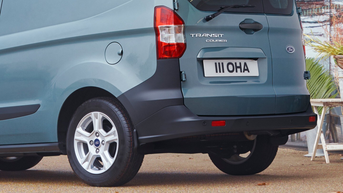Ford Transit Courier couleur grise. Vue arrière aux trois quarts avec pare-chocs en détail