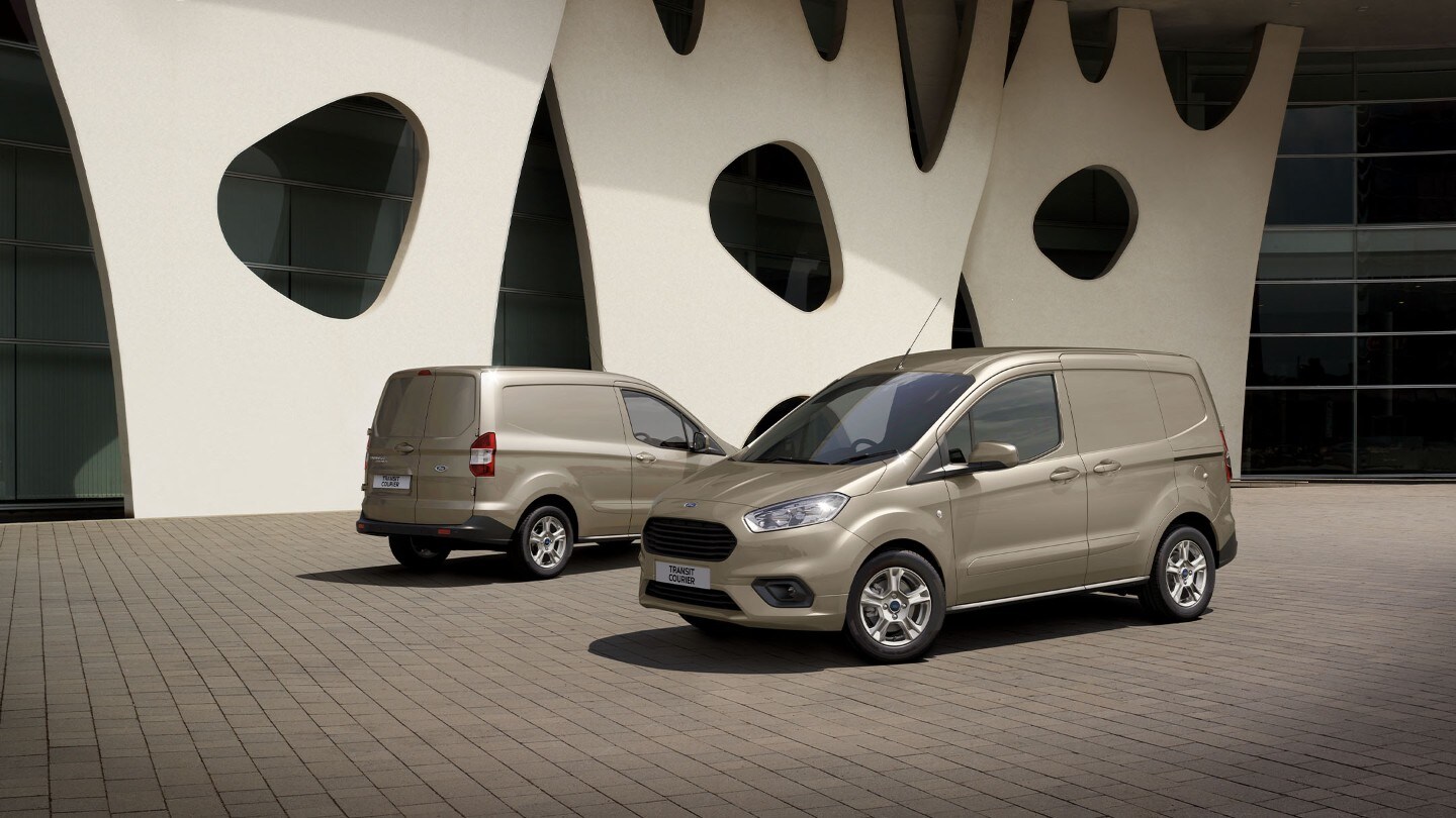 Ford Transit Courier en champagne respectivement en vue avant et arrière ¾ se garent l'un devant l'autre