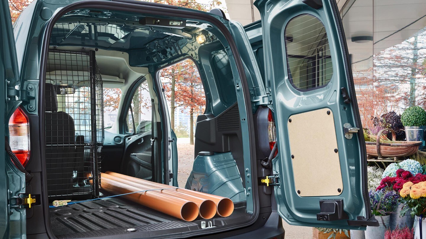 Ford Transit Courier avec chargement de tuyaux, vue arrière avec porte coulissante et hayon ouverts.