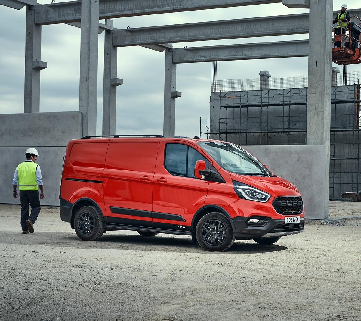 Fourgon Ford Transit Custom Trail rouge. Vue ¾ latérale. Stationnement sur un imposant chantier