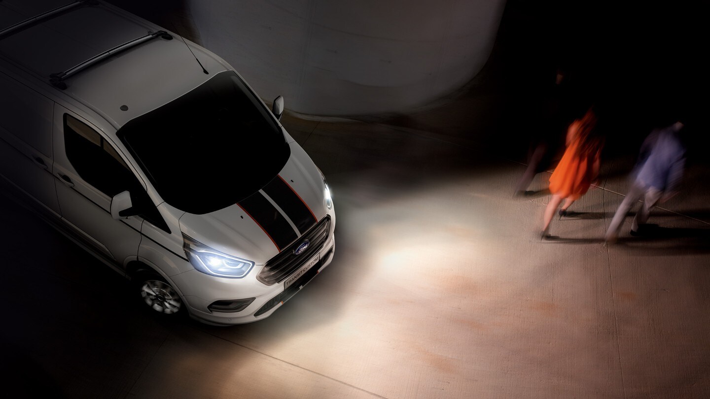 Ford Transit Custom couleur blanche, vue aérienne, phares éclairant la chaussée