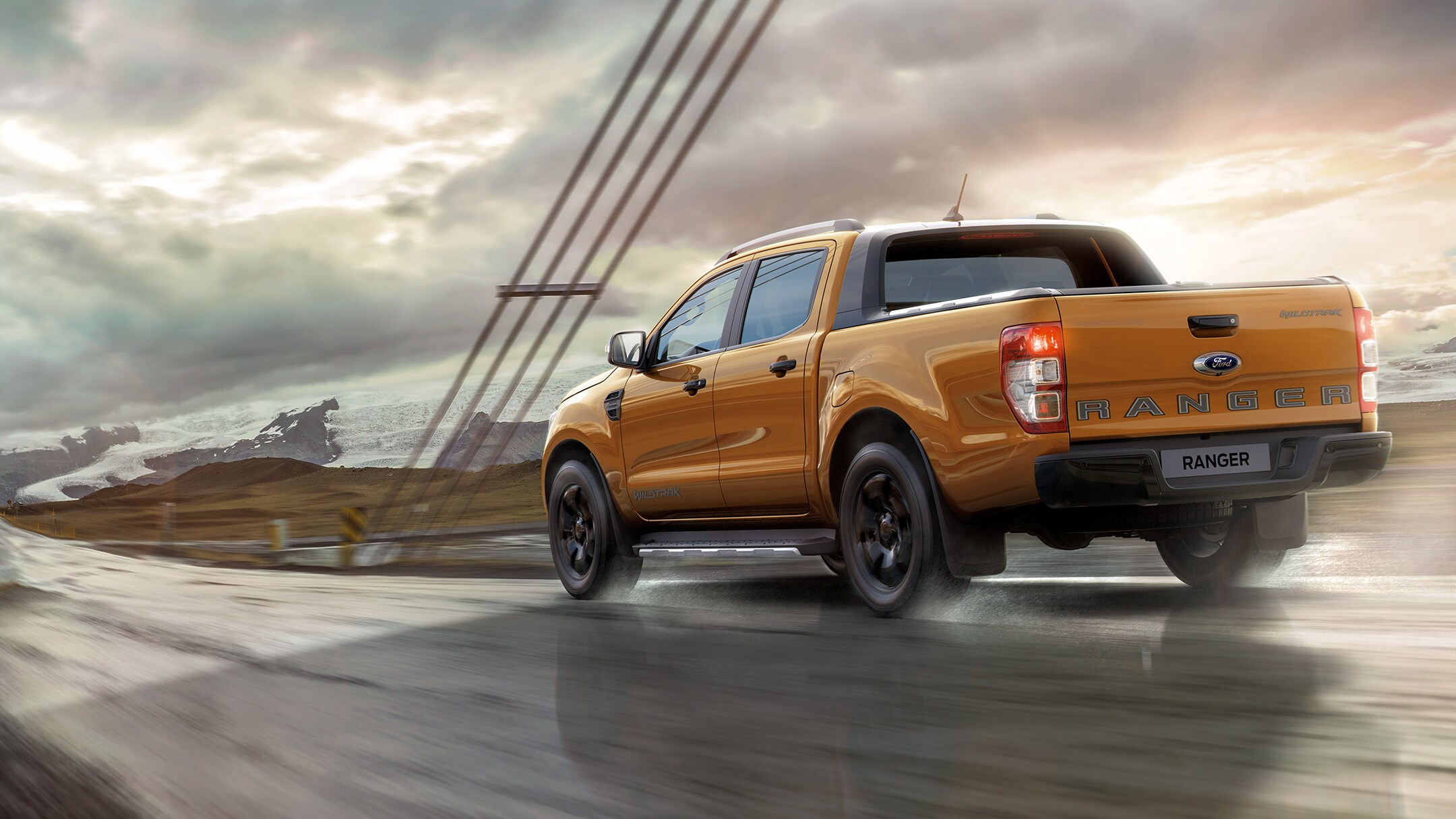 Ford Ranger couleur orange, vue arrière aux trois quarts, roulant sur un pont