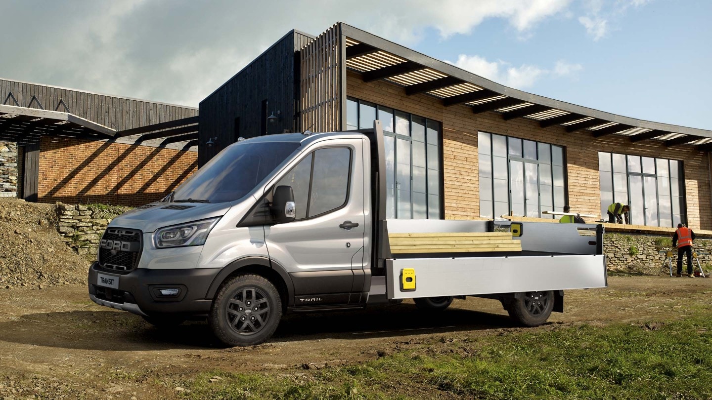 Ford Transit Plateau cabine couleur argent, vue latérale, chargé et stationné sur un chantier