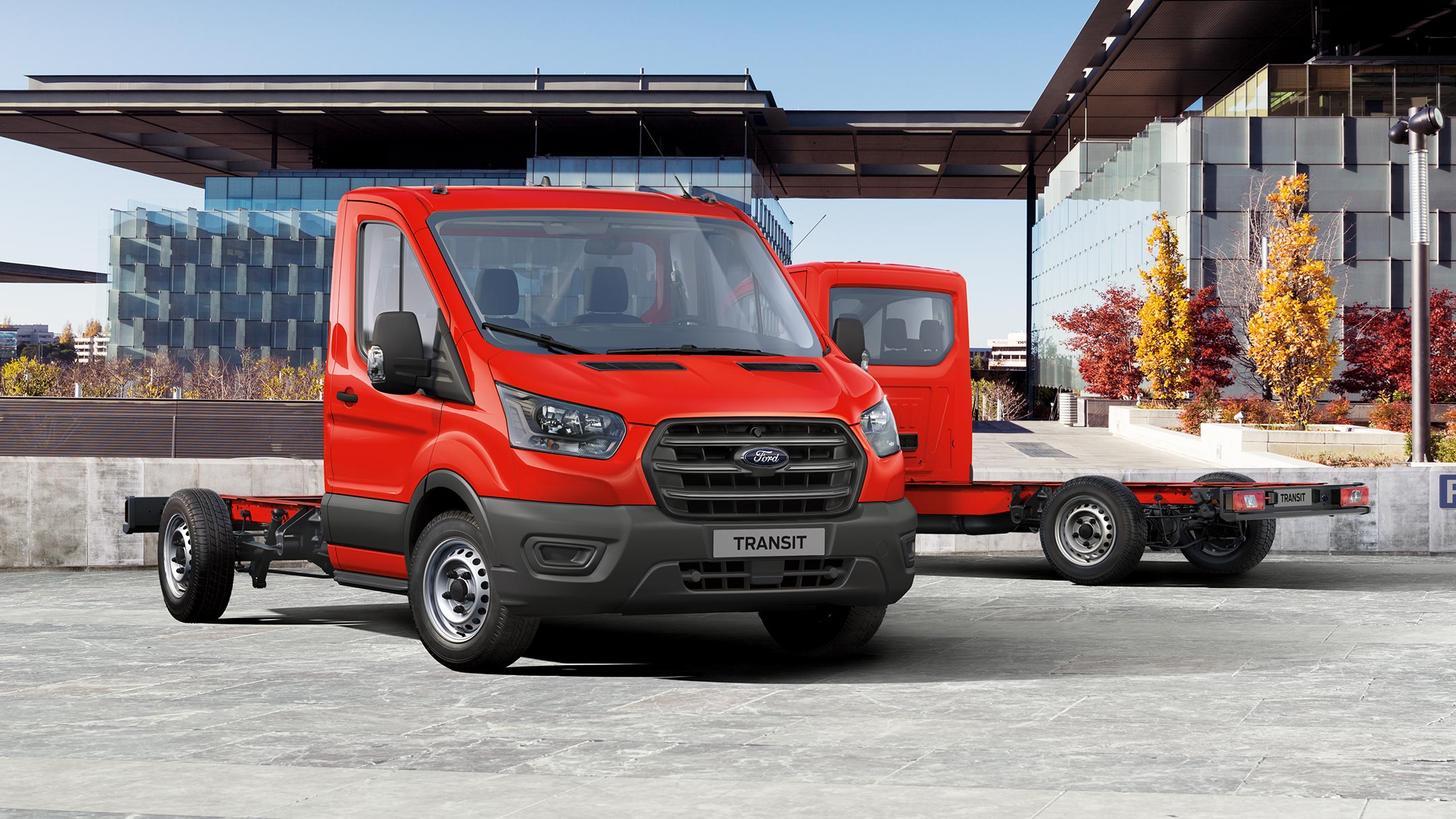 Ford Transit Châssis cabine couleur rouge, vue de face aux trois quarts, stationnant devant un bâtiment