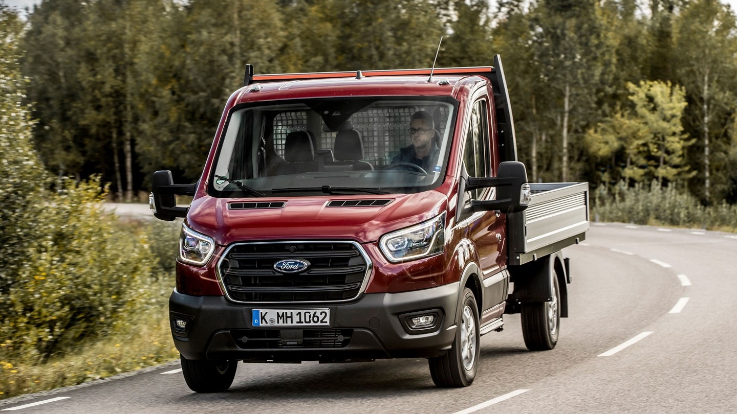 Ford Transit Châssis cabine couleur rouge, vue de face aux trois quarts, roulant sur une route